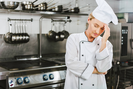 穿制服的漂亮疲惫的女厨师，在餐厅厨房和复印室头痛