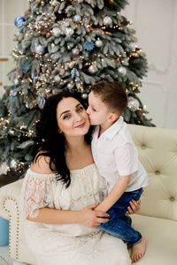 美丽的母亲和儿子在圣诞树附近的沙发上