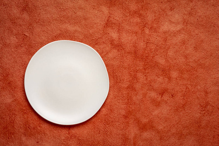 白色陶瓷板，边缘不规则的南瓜橙色手工胡恩马雅纸与复制空间