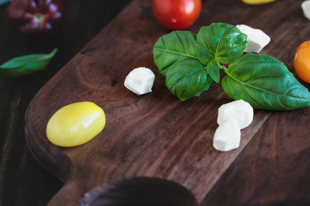 新鲜的花园罗勒和传家宝番茄与莫扎雷拉奶酪卡普雷斯沙拉，意大利食品和健康的素食概念，在一个乡村木制背景。