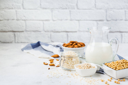 饮食保健饮食和营养理念。 厨房餐桌上坚果燕麦大豆有机纯素非日记本牛奶的品种。 复制背景
