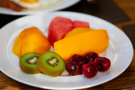 充满新鲜切片异国水果的盘子猕猴桃甜樱桃芒果木瓜和西瓜，美味健康的小吃