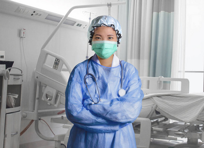 年轻自信成功的亚洲韩国医学博士，女性，在医院擦洗和口罩，在医疗保健的诊所病人床上摆姿势，作为公司医生肖像。