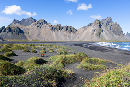 一家两口父子，在美丽的斯托克斯内斯半岛黑沙滩散步，欣赏冰岛维斯塔霍恩山脉风光，积极的度假理念