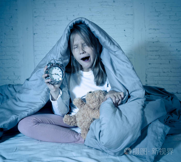 可爱的失眠小女孩坐在床上,看着悲伤和疲惫,有睡眠