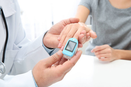 s pulse with medical device at table in hospital, closeup