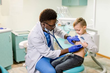 s doctor examining little boy with stethoscope in hospital