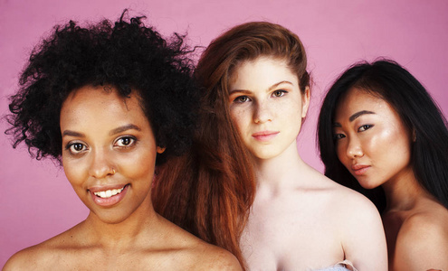 三个不同的民族女孩, 皮肤头发有分。亚洲人, 非洲裔美国人, 白种人在粉红色的背景