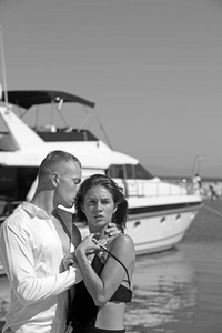 的女人和男人在海湾。的女人与红色的嘴唇和男人亲吻她的脖子附近的游艇