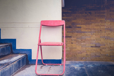 老式折叠椅和旧墙。 复古色调颜色