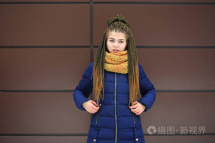 一个年轻漂亮的白人女孩,戴着一条黄色针织围巾,穿着蓝色夹克,在冬天