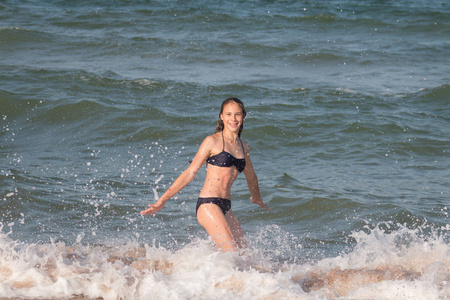 夏天，一个年轻漂亮的女孩留着长发，13岁，14岁，在海边的海浪中嬉戏