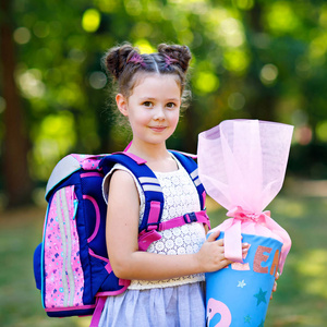 快乐的小女孩与背包或背包和大书包或圆锥传统在德国的第一天的学校。健康可爱的孩子在户外, 在绿色公园