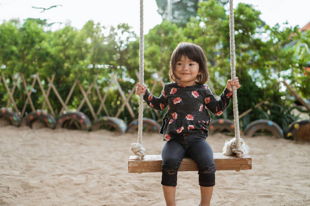 亚洲小女孩享受独自在公园玩秋千