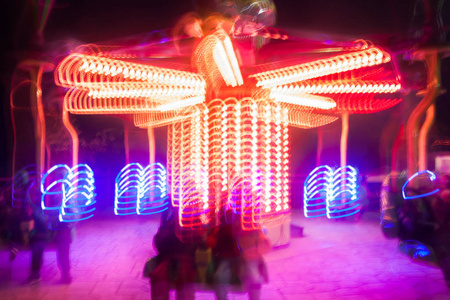一个模糊的彩色旋转木马在游乐园夜间照明。 Bokeh和长时间暴露的影响