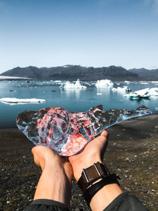 s hands hold a whale ice piece against the jokulsarlon glacier l