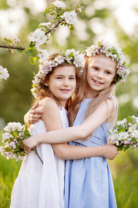 美丽的年轻女孩穿着长长的连衣裙在花园里，绿树成荫。 微笑的女孩拥抱乐趣，享受