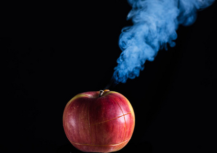 黑背景下的红苹果正在吸烟