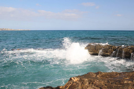 海浪拍打在岸边的一块大石头上，白色的飞溅，清澈的海上度假