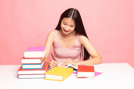 年轻的亚洲女人读一本书，上面放着粉色背景的书