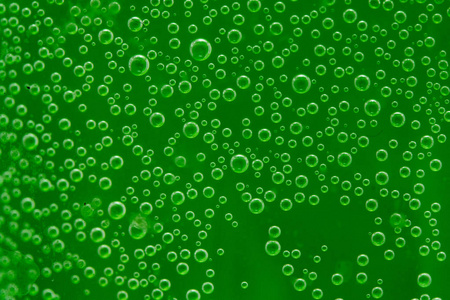 绿色背景下水中的圆形空气滴
