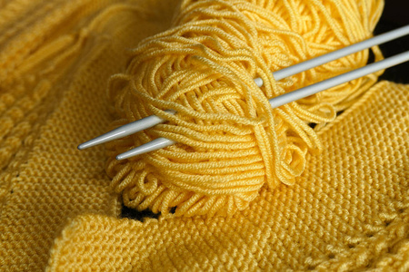手工编织的针织针在黑色的背景和黄色的圆绳，用于制作黄色的手工编织圆绳