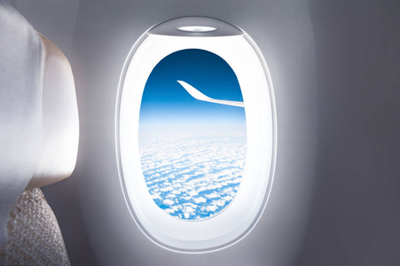 飞机窗的天空和飞机的机翼视图。旅行和度假概念