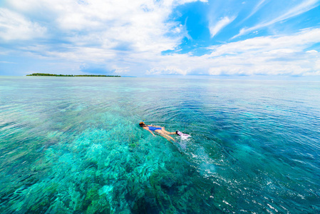 女子浮潜在珊瑚礁热带加勒比海绿松石碧水。 印尼瓦卡托比海洋国家公园游客潜水旅游目的地