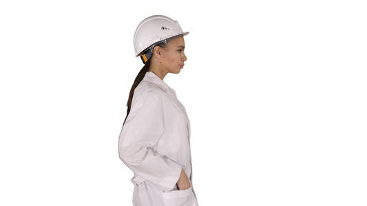 妇女在白色长袍投入硬帽子, 而走在白色背景
