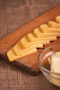奶酪片放在靠近黄油和牛奶的木桌上