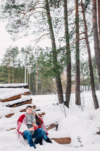 在冬天的森林里, 微笑的夫妇裹在毯子里, 在户外喝茶