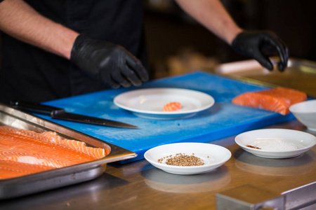 s hand in a restaurant kitchen preparing red fish fillets salmon