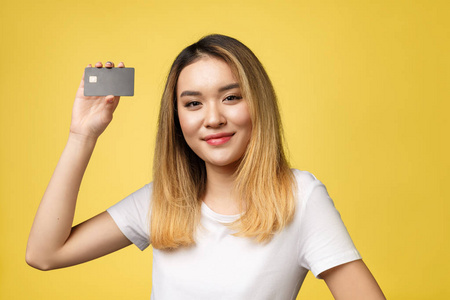 年轻的微笑美丽的亚洲女人拿着信用卡在手, 表现出信任和信心的支付