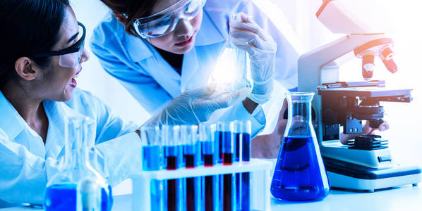 一组科学家穿着实验室外套在实验室工作，同时检查试管和科学仪器中的生物化学样品。 科学技术研发研究理念。