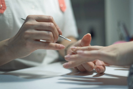 美甲师在女性指甲上使用指甲刮。 指甲护理概念。