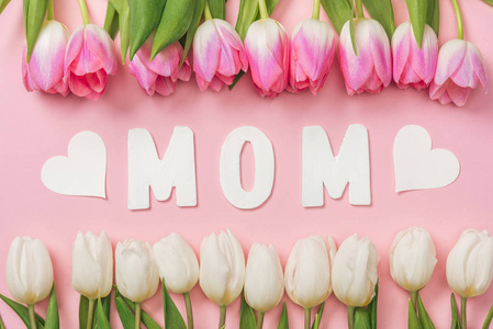 粉红色和白色郁金香排列成一排，中间有纸字妈妈，粉红色的背景