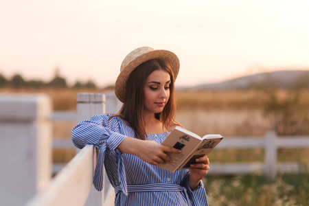 美丽的孕妇在农场上读这本书。她站在法朗斯旁边, 看着这本书。放松