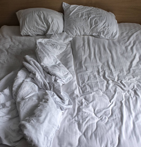白色床上用品床单和枕头的顶部视图。