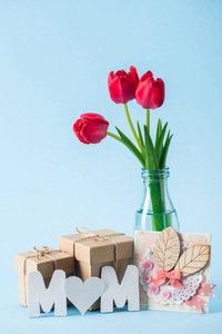 母亲节贺卡礼品盒红色郁金香花束和蓝色背景上心形垃圾的纸字妈妈