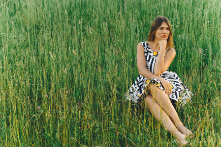 穿着裙子坐在绿草地上的年轻女子