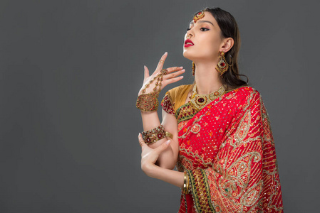 有吸引力的印度女人用传统的纱丽做手势，并用灰色隔离配饰