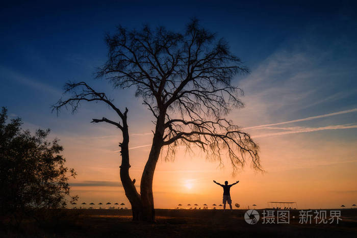 海滩上树下人的剪影. 地中海上空的橙色日出. 在土耳其的清晨.
