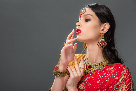 有吸引力的印度女人用灰色隔离的饰物做手势