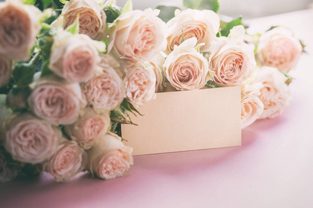 粉红色玫瑰花，粉红色背景上有礼品卡。母亲节生日情人节妇女节庆祝理念。文字空间。