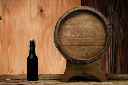 木桶和黑色啤酒瓶在一张古老的橡木桌上。