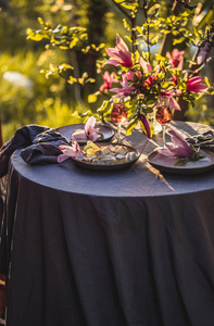 美丽的桌子设置在花园的日落灯光下。在木兰树下装饰着玉兰花的桌子