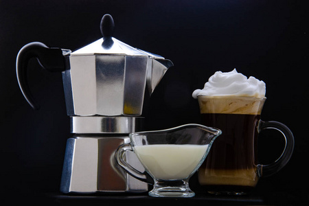 一杯咖啡牛奶壶和一个咖啡壶。 黑色背景。