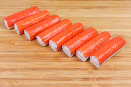 在木竹砧板上撒满奶酪的蟹条