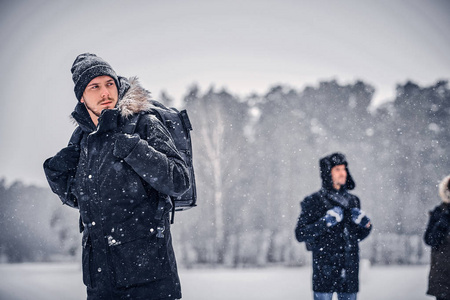 一个年轻的徒步青年, 背着背包和他的朋友们一起在冬林里散步