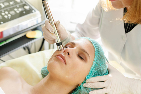 美容美容美容及科技理念美容专家在美容院对一位年轻美女面部皮肤进行微电流治疗